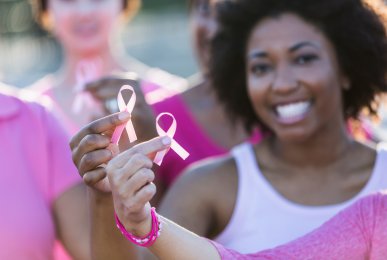 Group of multi-ethnic women holding breast cancer awareness ribbons in their hands and wearing pink shirts