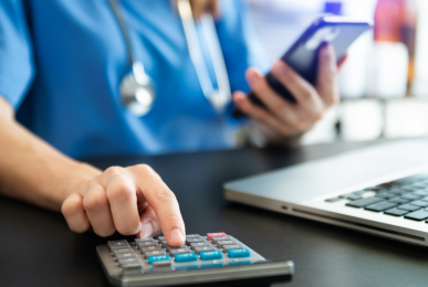 Healthcare professional using a laptop and calculator. 