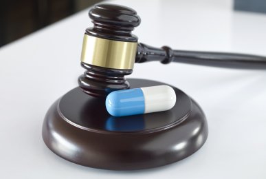 Pill on a gavel on top of a desk in a court room