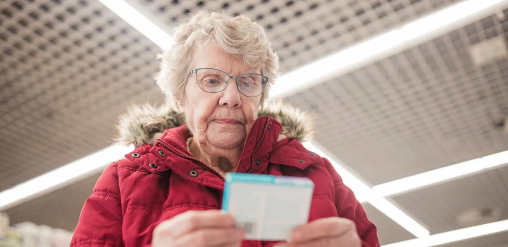 A senior woman looking at a prescription receipt.