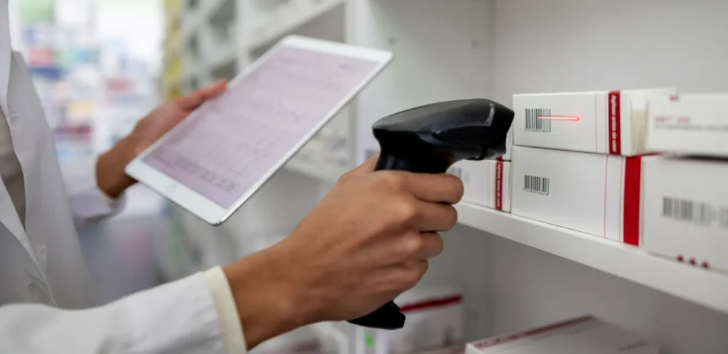 Pharmacist taking inventory at the drugstore using a bar code reader