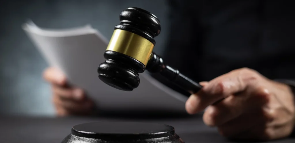 Close-up of judge holding gavel and legal documents in courtroom setting